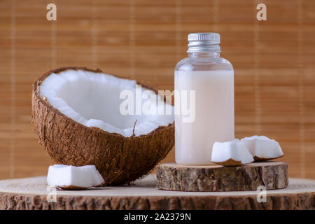 Bouteille cosmétique et noix de coco fraîche pour la peau, fond brun naturel Banque D'Images