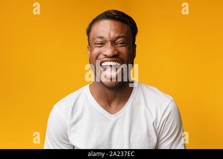 LOL. African American Man émotionnelle Laughing Out Loud Looking at Camera Standing In Studio sur fond jaune. Banque D'Images