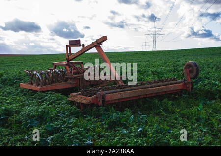 Herse du disque en stationnement sur terrain vert en automne Banque D'Images