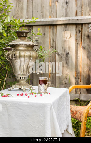 Samovar en cuivre vintage dans un porte-gobelet et un verre de thé chaud est sur la table sont dispersées les cerises et les framboises, ainsi vaut la chaire en Ru Banque D'Images