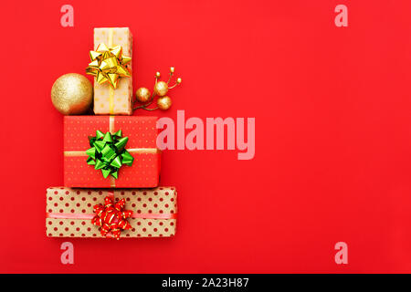 Composition de Noël. Cadeaux de Noël disposés dans la forme d'un arbre de Noël sur fond rouge. Mise à plat, vue du dessus, copiez l'espace. Banque D'Images