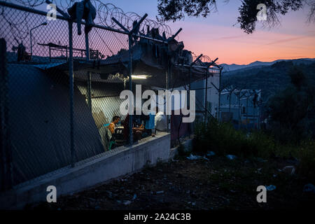 Athènes, Grèce. 26 Sep, 2019. Les migrants s'asseoir dans la Moria camp sur l'île de Lesbos à côté d'une clôture en fil barbelé. Angelos Tzortzinis : Crédit/dpa/Alamy Live News Banque D'Images
