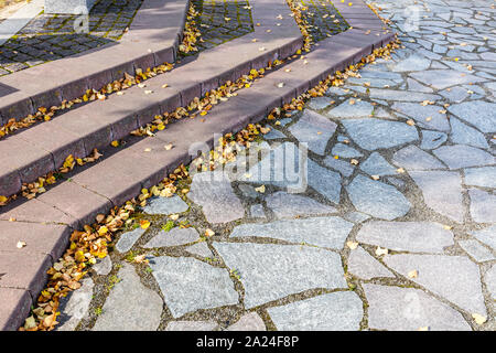 Escalier de pierre recouvert de feuilles jaunes secs tombés ensoleillée journée d'automne. Banque D'Images