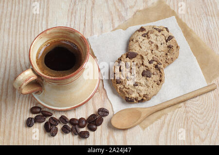 Tasse de café et des biscuits avec du chocolat sur un papier placé sur une table en bois Banque D'Images