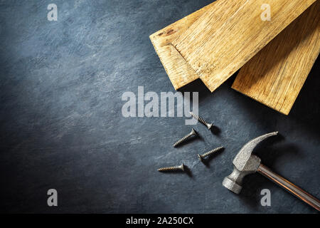 Marteau et du bois sur fond de ciment noir. Vue de dessus et copiez l'espace pour le texte. Concept de carpenter ou de construire. Banque D'Images