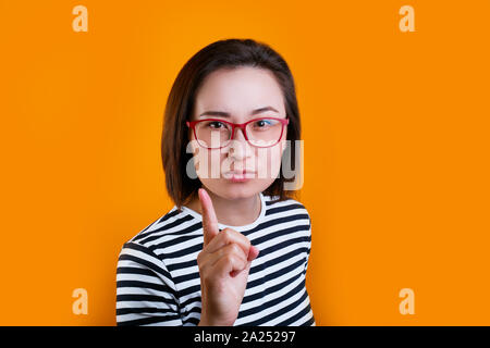 femme asiatique mécontenté dans des verres rouges avertissement sur fond jaune Banque D'Images