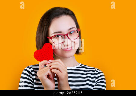 Portrait d'une jolie fille asiatique tenant le cœur rouge isolé arrière-plan jaune Banque D'Images