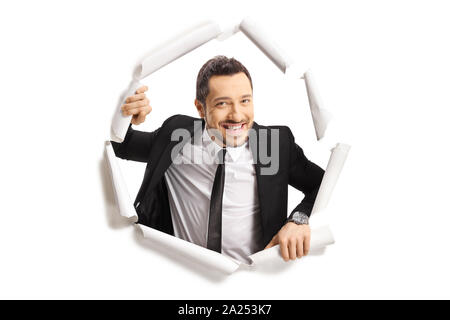 Jeune homme en costume de regarder à travers un trou du papier isolé sur fond blanc Banque D'Images