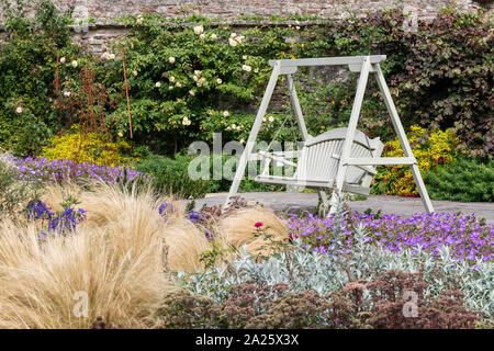 Un swing en bois peint banc dans le magnifique jardin de la palais des évêques, Wells, Somerset, UK Banque D'Images