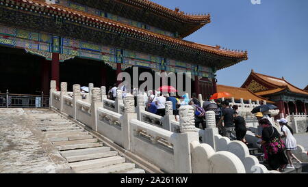 Des foules de touristes chinois visiter la Cité Interdite, à Pékin, en Chine. De nombreux parasols UV transporter à l'abri du soleil implacable une fois qu'ils atteignent le terrain ouvert. Banque D'Images