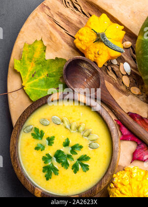 Crème de potiron, carotte, soupe de lentilles avec les graines de citrouille, le persil dans un bol en bois, boiseries de chêne citrouille et feuillage de l'automne, l'automne des aliments sains, veg Banque D'Images