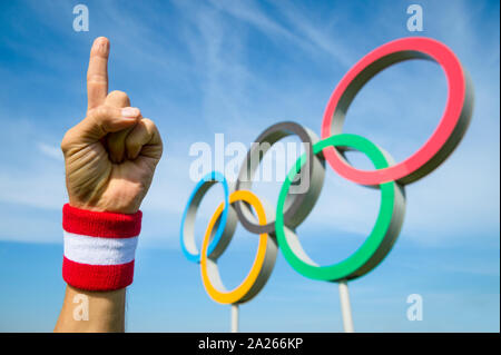 RIO DE JANEIRO - le 15 mars 2016 : une main porter du rouge et blanc avec un certain nombre de points bracelet un doigt pour le sky air en face d'anneaux olympiques. Banque D'Images