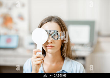 Jeune femme contrôle de vision avec l'essai d'oeil lunettes lors d'un examen médical à l'office d'ophtalmologie Banque D'Images