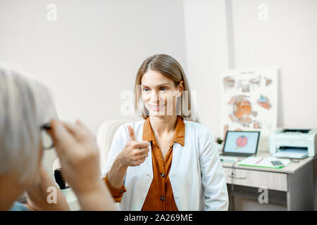 Ophtalmologiste femelle consulting senior woman, conseiller lunettes pour une vision dans le bureau d'ophtalmologie Banque D'Images