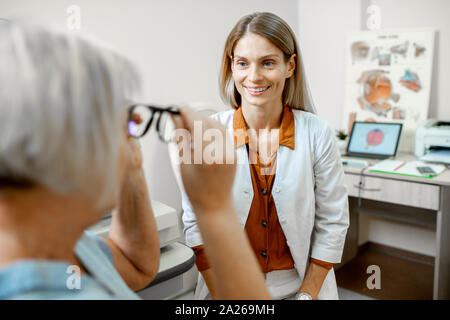 Ophtalmologiste femelle consulting senior woman, conseiller lunettes pour une vision dans le bureau d'ophtalmologie Banque D'Images