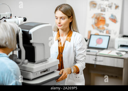 Les yeux de couples a senior patient à l'aide de microscope digital durant un examen médical dans le cabinet d'ophtalmologie Banque D'Images