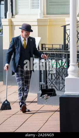 Grand Hotel Brighton portier portant des uniformes intelligents et chapeau melon balayant les ordures jusqu'à l'extérieur de l'hôtel. Banque D'Images