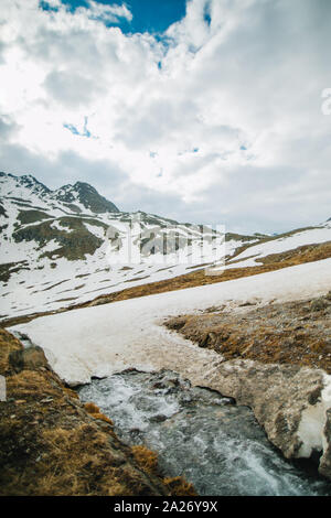 La présentation détaillée de l'eau coule sous la glace dans une rivière. La neige fond des montagnes et s'écoule en ruisseau, Close up. Banque D'Images