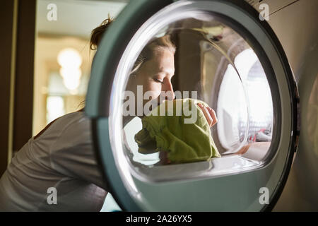 Femme les odeurs de linge propre frais de la machine de lavage après lavage Banque D'Images