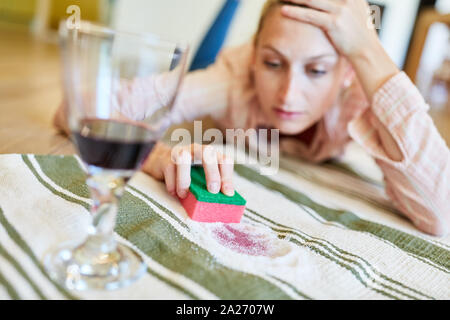 Femme au foyer laborieusement supprime la tache de vin rouge du tapis avec le sel et l'éponge Banque D'Images