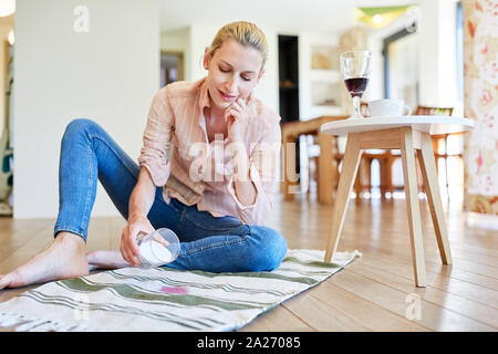 Femme supprime le vin rouge sur la moquette avec du sel comme remède à la maison Banque D'Images