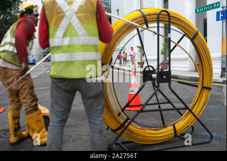 15.04.2018, Singapour, Singapour , - Deux travailleurs sont la pose de câbles sur une rue dans le quartier des affaires. 0SL180415D010CAROEX.JPG [communiqué de modèle : NON, P Banque D'Images