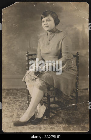 Portrait d'une femme assise sur une chaise, face vers la gauche Banque D'Images