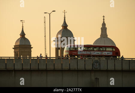 Long Shot de piétons et bus traversant le pont de Londres au coucher du soleil. Le plan général de St Pauls est dans l'arrière-plan Banque D'Images