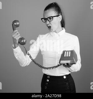 Angry businesswoman crier au téléphone tourné en noir et blanc Banque D'Images