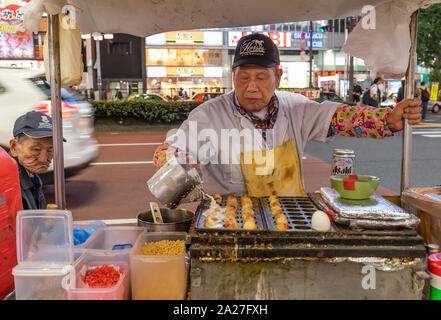 Tokyo, Japon - 29 octobre 2018 : Un vendeur de rue de la préparation d'aliments de rue japonais, takoyaki, sur un trottoir de Tokyo, Japon Banque D'Images