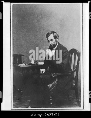 Le président Abraham Lincoln, assis à côté d'une petite table, dans une posture réflexive, le 16 mai 1861, avec son chapeau visible sur la table Banque D'Images