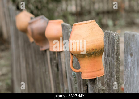 Les cruches d'argile brun accroché à une clôture en bois en Ukraine. Vintage décoration rurale traditionnelle Banque D'Images
