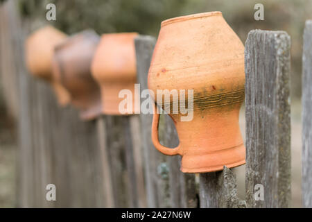 Les cruches d'argile brun accroché à une clôture en bois en Ukraine. Vintage décoration rurale traditionnelle Banque D'Images