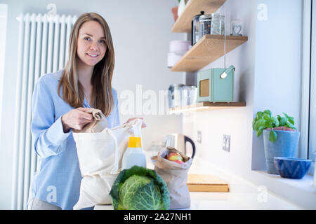 Portrait de femme au retour de voyage d'achats d'épicerie en plastique dans le déballage des sacs gratuits Banque D'Images