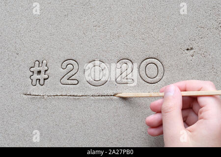 Dessin à la main de l'enfant signe hashtag et nombre 2020 sur le sable humide. Bonne Année 2020 ! Banque D'Images