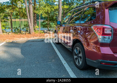 Un SUV sportif rouge garé au bord du lac pour le plaisir et l'aventure à l'extérieur sur une belle journée ensoleillée en été Banque D'Images