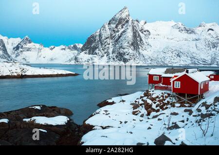 Maison en bois traditionnelle norvégienne rorbu de se tenir sur la rive du fjord et des montagnes au loin. Iles Lofoten. La Norvège. world travel Banque D'Images