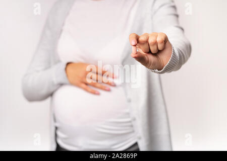 Fille enceinte montrant comp toucher Belly Over White Background, Cropped Banque D'Images