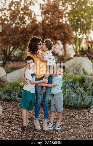 Portrait de Mère kissing son avec les garçons l'étreindre dans le jardin ensoleillé Banque D'Images