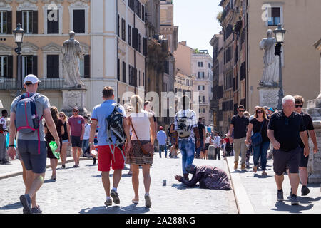 Personnes âgées femme mendiant à genoux au milieu de la foule des touristes sur le pont en direction de la Cité du Vatican. Marché autour et ignorés. Banque D'Images