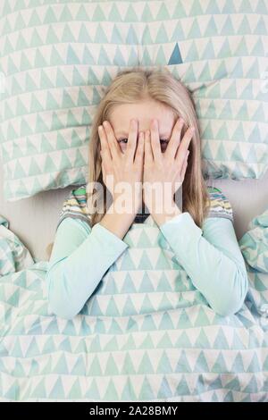 Petite fille se trouve au lit avant le coucher. le sommeil et la santé Banque D'Images