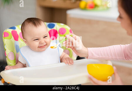 Cheerful baby manger en cuisine dans une chaise haute Banque D'Images