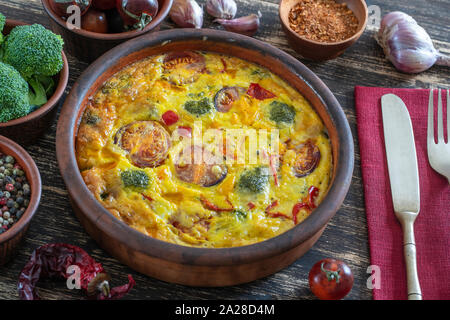 Frittata aux légumes avec bol en céramique, la nourriture végétarienne simple. La Frittata avec des œufs, de la tomate, le poivron, l'oignon, le brocoli et fromage,. Banque D'Images