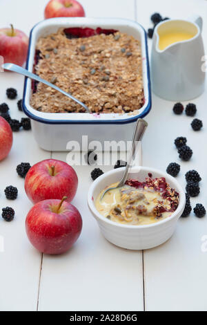 Blackberry fait maison et crumble aux pommes et crème anglaise avec une cuillère à soupe. L'avoine biologique et de graines mûres recherchent leur nourriture crumble aux pommes et Banque D'Images