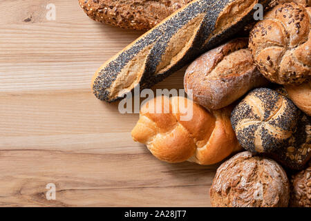 Petits pains et baguettes mixtes sur bois clair. Vue d'en haut. L'espace pour le texte. Banque D'Images