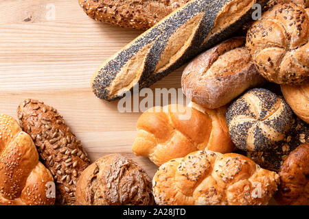 Petits pains et baguettes mixtes sur bois clair. Vue d'en haut. L'espace pour le texte. Banque D'Images