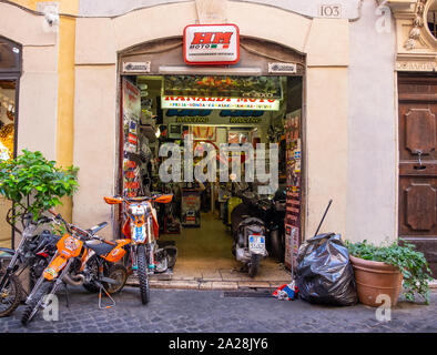 Paniers colorés afficher et atelier sur la rue et l'intérieur d'une petite boutique étroite dans le centre de Rome, pour les motos et scooters. Sac poubelle à l'extérieur. Banque D'Images