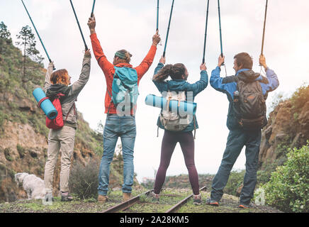 Groupe d'amis, élever les mains en tenant les bâtons de trekking sur un pic de montagne - Les jeunes à la découverte de la nature Banque D'Images