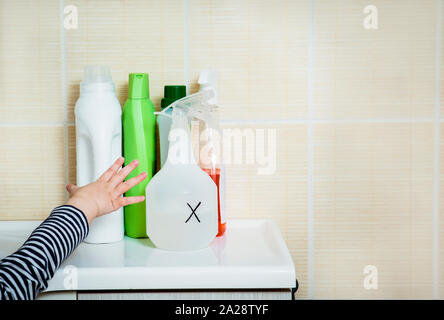 Petit enfant tend la main aux produits chimiques ménagers. Garder hors de portée des enfants. Dangers à la maison pour les enfants concept. Banque D'Images