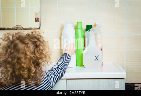 Petit enfant tend la main aux produits chimiques ménagers. Garder hors de portée des enfants. Dangers à la maison pour les enfants concept. Banque D'Images